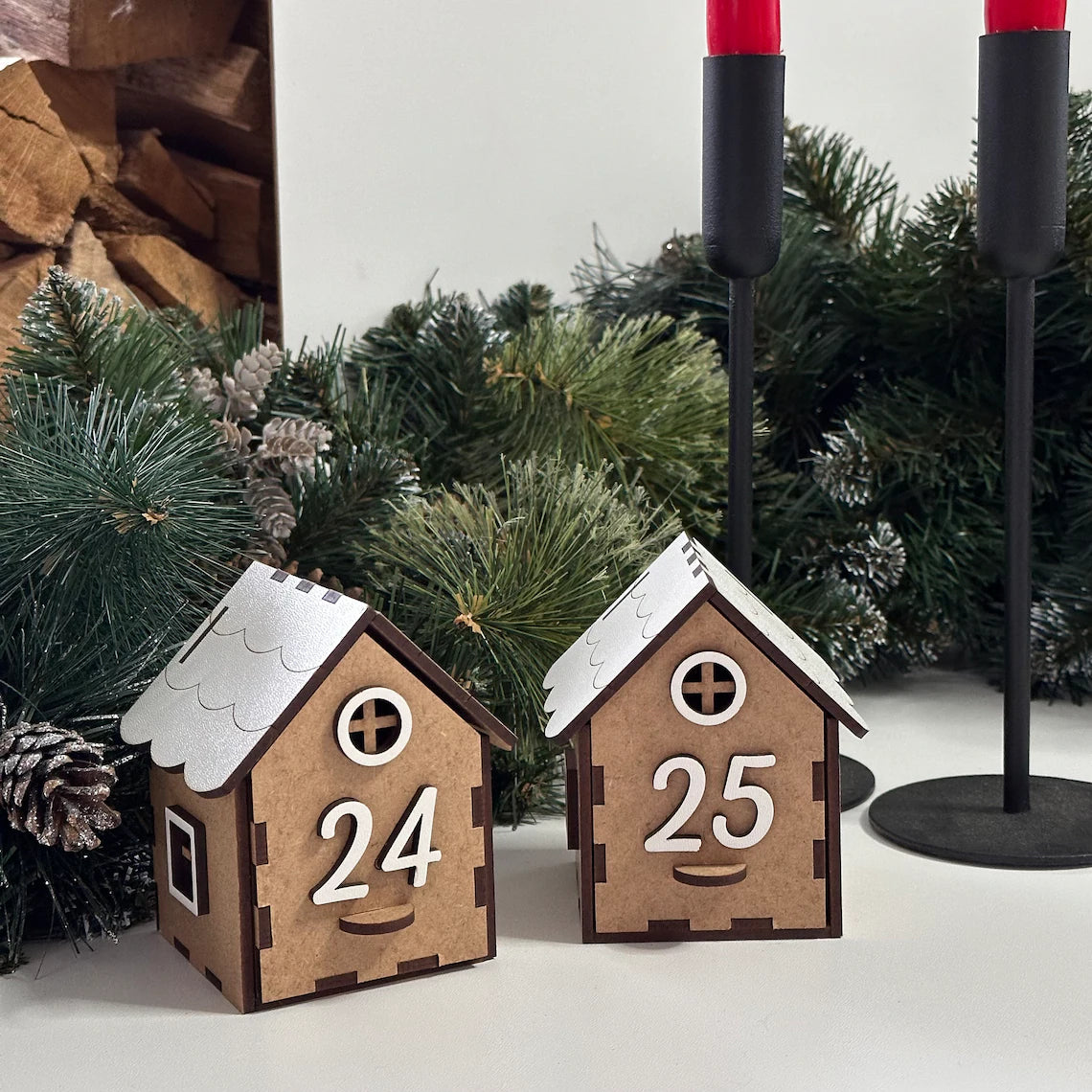 Two wooden house-shaped Advent calendar pieces with numbers 24 and 25, surrounded by Christmas decorations.