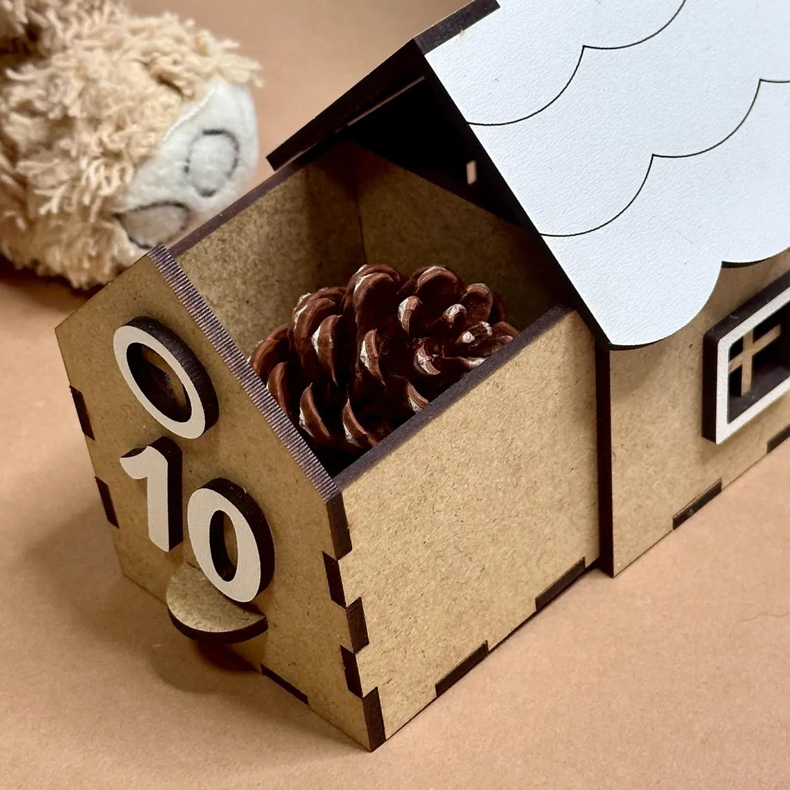 Advent calendar with pine cone and wooden numbers on a beige surface