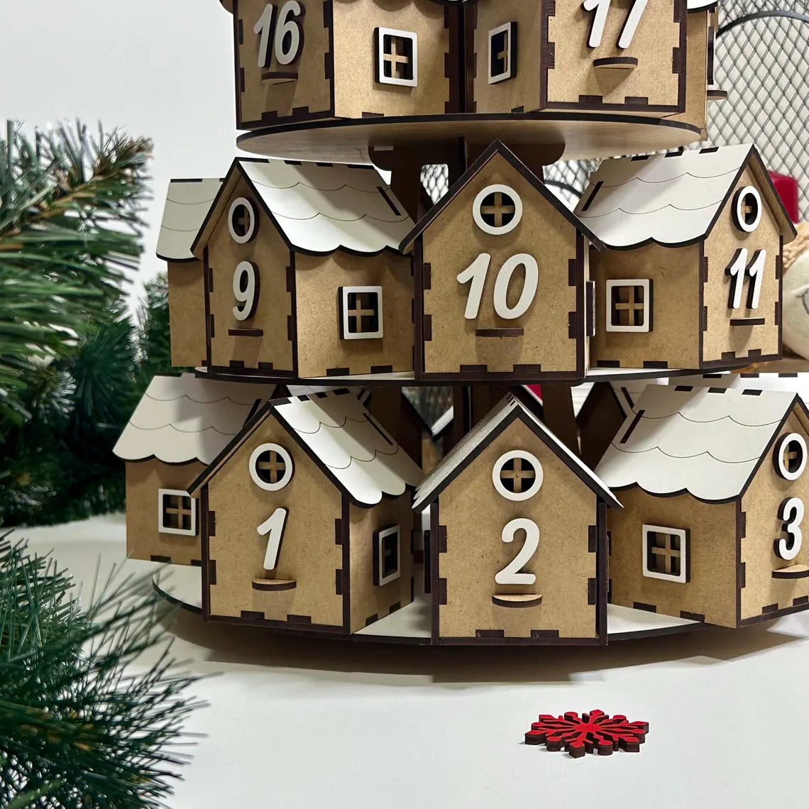 Wooden advent calendar with houses and numbers, Christmas tree in the background
