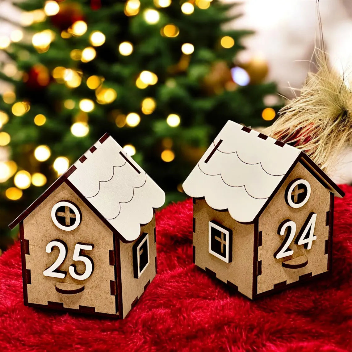 Two wooden house-shaped Advent calendar pieces with numbers '25' and '24' in front of a Christmas tree.