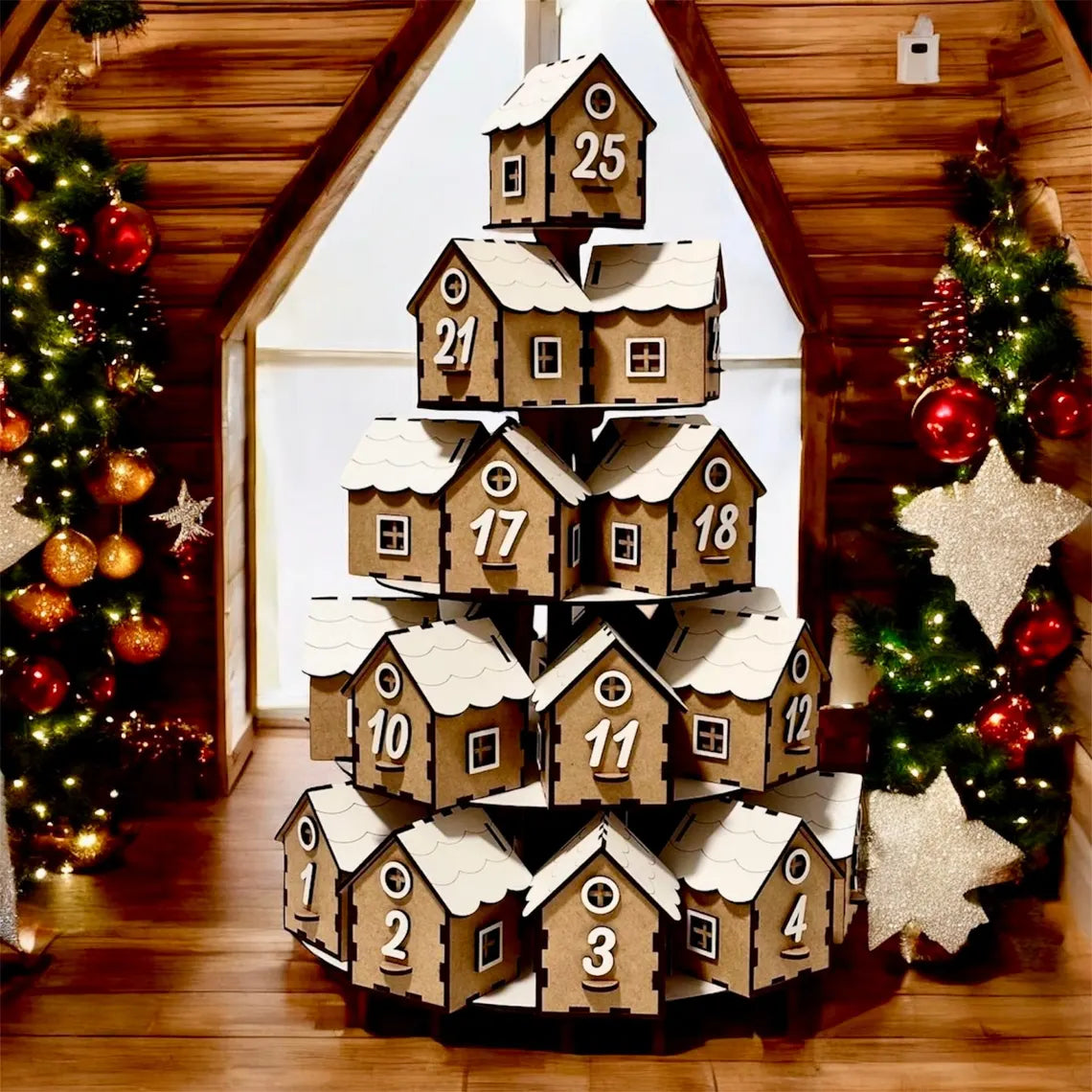 Wooden advent calendar shaped like a snow-covered village with Christmas trees and decorations in the background.