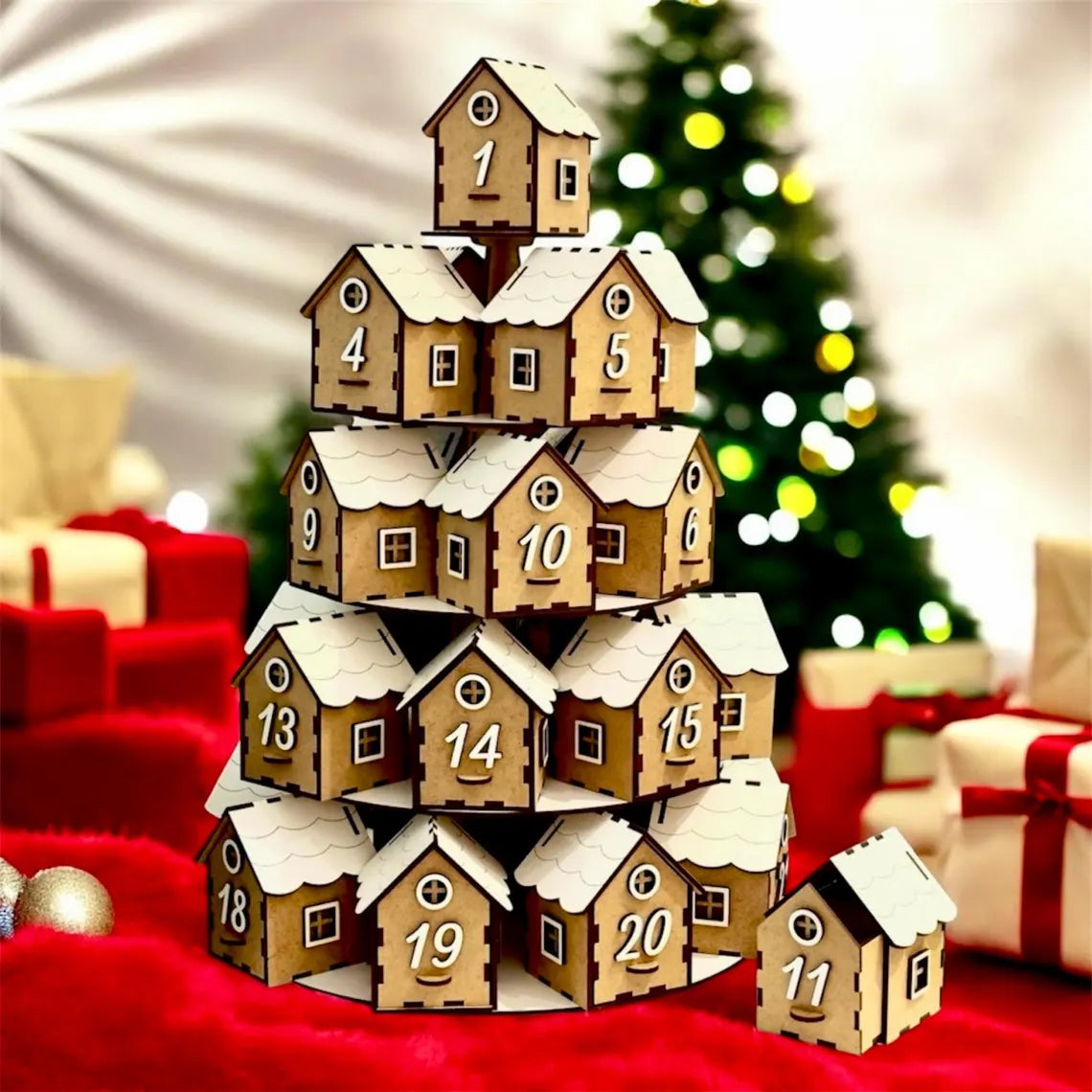 Wooden advent calendar with snow-covered houses in front of a Christmas tree and presents.