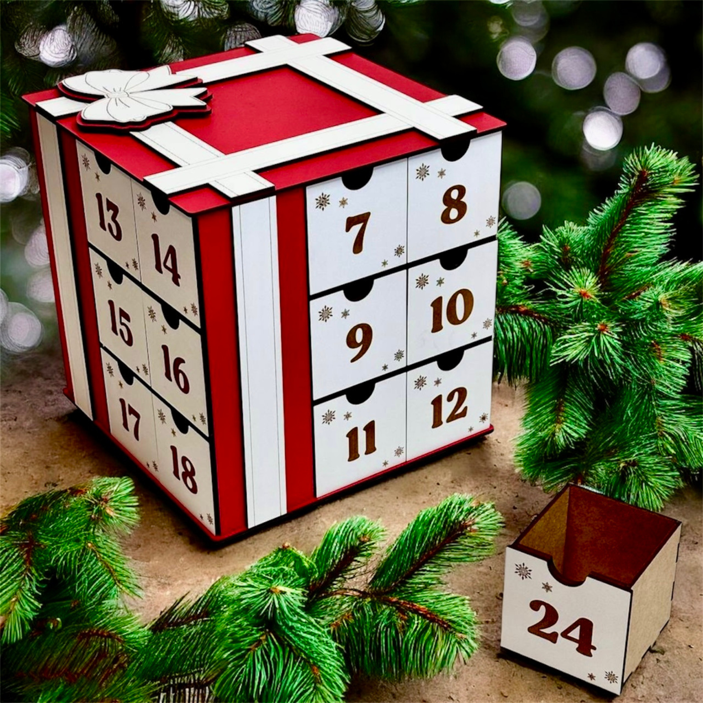Advent calendar with red and white design, surrounded by Christmas tree branches.