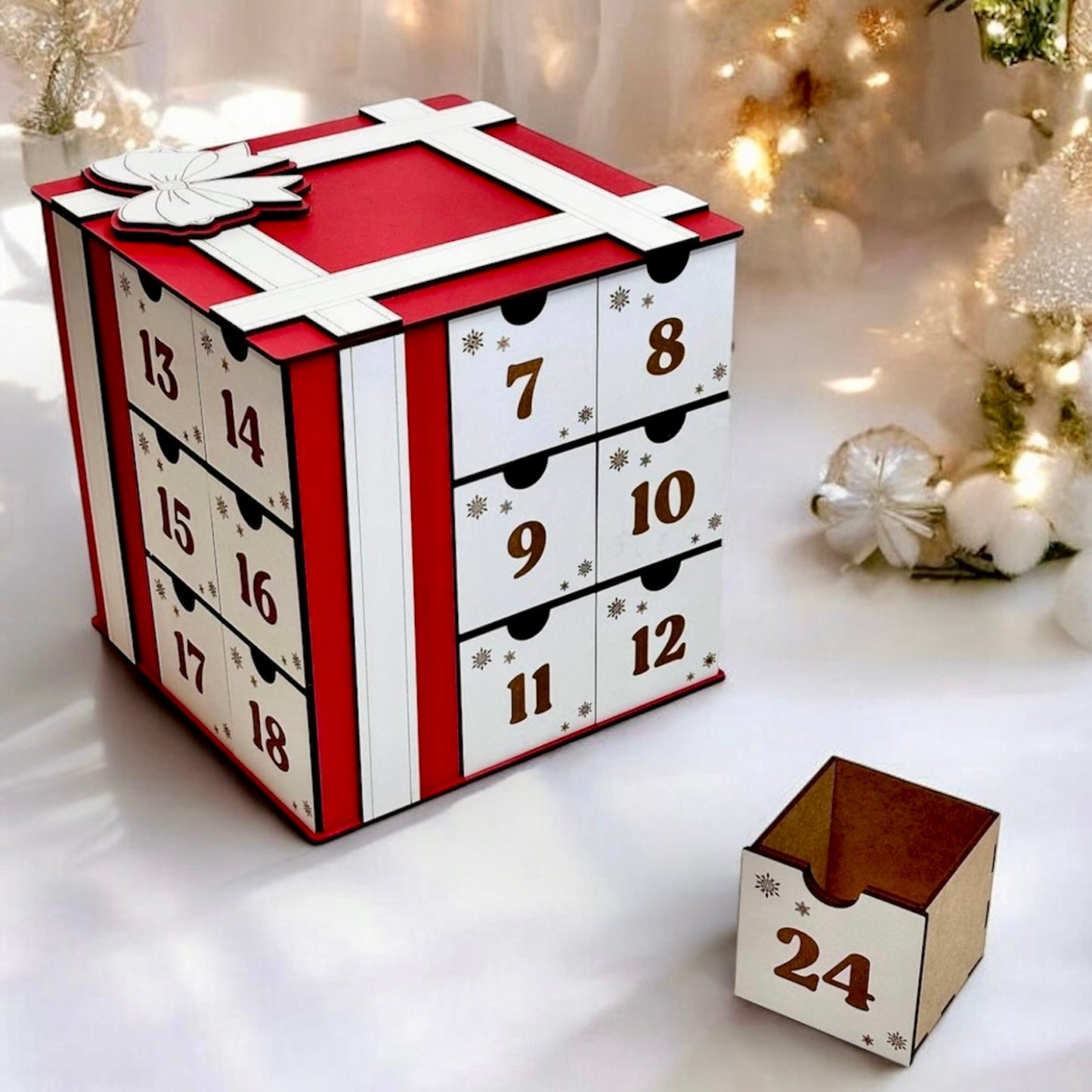 Advent calendar with numbered drawers on a white surface with Christmas decorations.