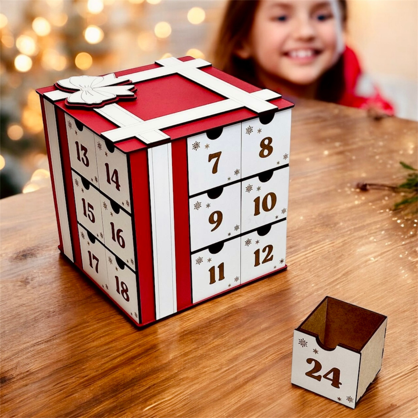 Advent calendar with numbered drawers on a wooden surface, blurred child in the background