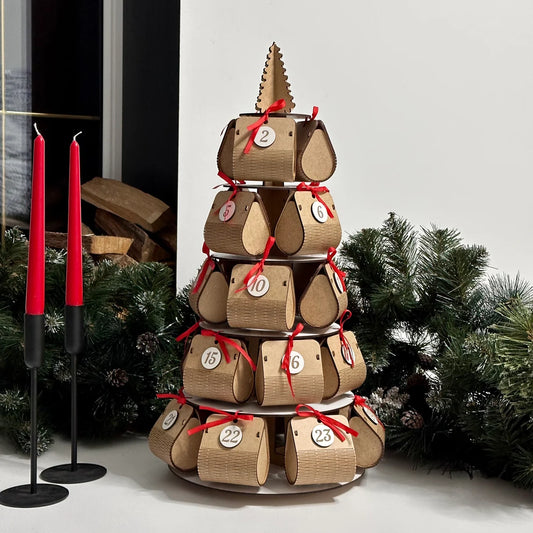 Wooden advent calendar stacked in a tower with Christmas decorations in the background.