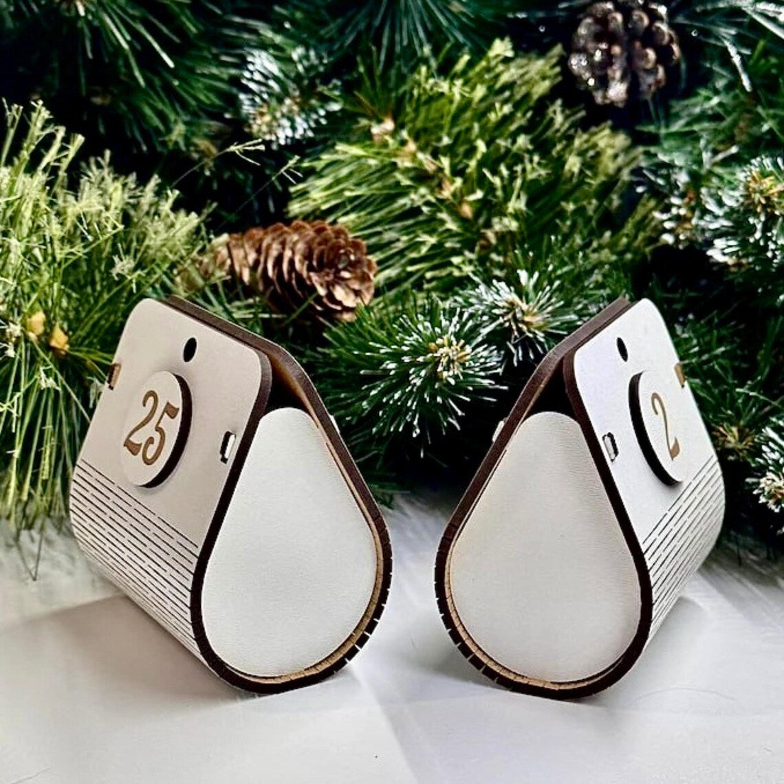 Two wooden advent calendar pieces with numbers on a Christmas tree background