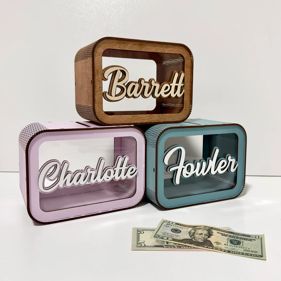 Three decorative name boxes labeled 'Barrett', 'Charlotte', and 'Fowler' on a white background with a dollar bill.
