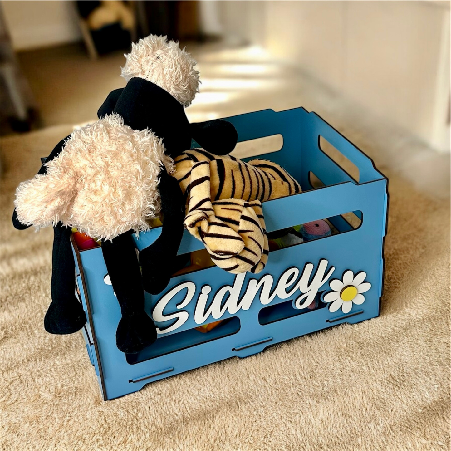 Blue toy crate with stuffed animals on a carpeted floor