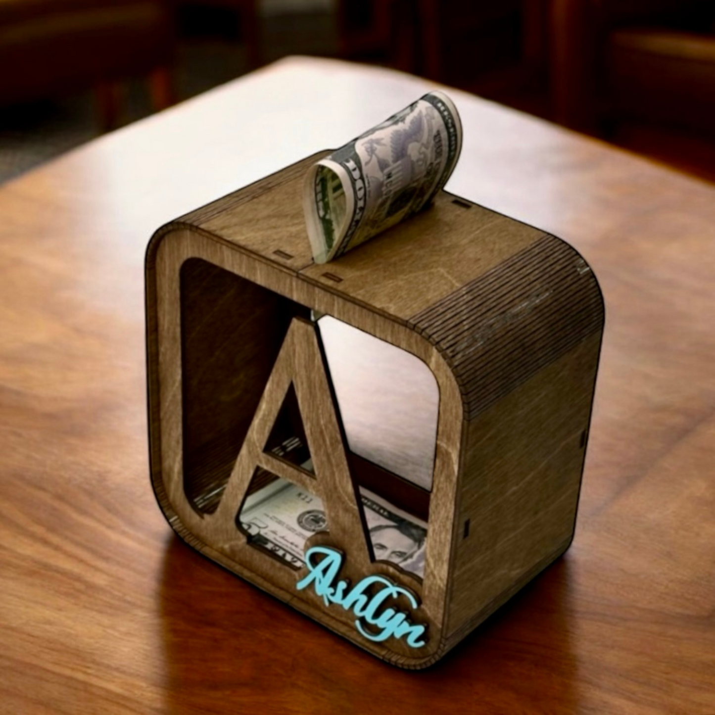 Wooden money box with 'Ashlyn' engraving on a wooden surface