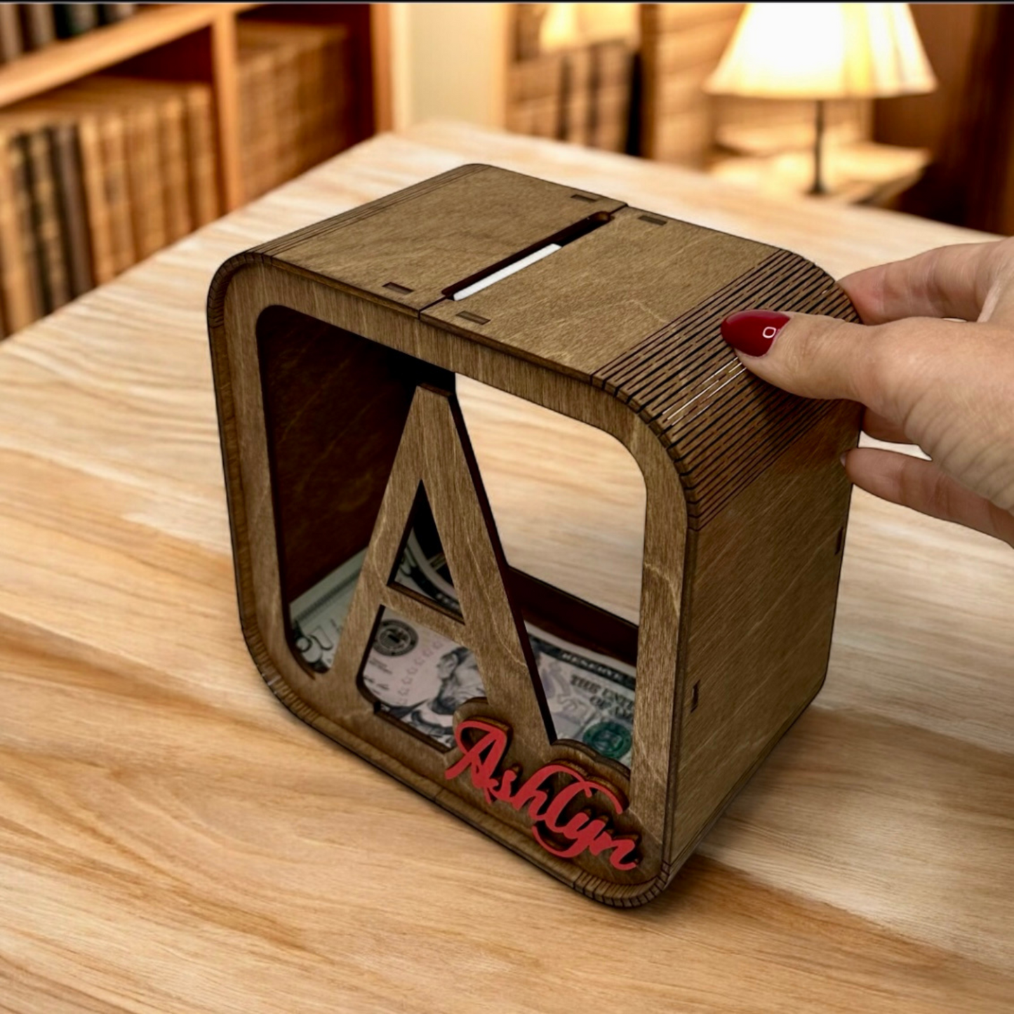 Wooden money box with 'Ashlyn' engraving on a wooden surface